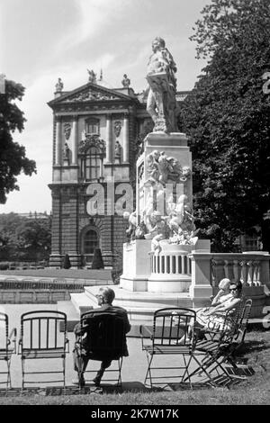 Seitenansicht vom Mozart-Denkmal von Viktor Oskar Tilgner im Burggarten mit Besuchen, Österreich 1962. Seitenansicht des Mozart-Denkmals von Viktor Oskar Tilgner im Burggarten mit Besuchern, Österreich 1962. Stockfoto