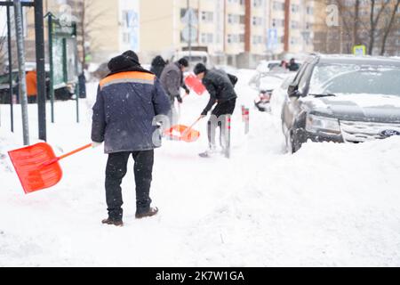 Russland Moskau 13.02.2021 Straßenreiniger, Männer reinigen Schnee von der Straße, Bürgersteig mit großen Schaufeln. Stadt Winter Wetter Zusammenbruch, Schneefall, Schneeverwehungen. Ca Stockfoto