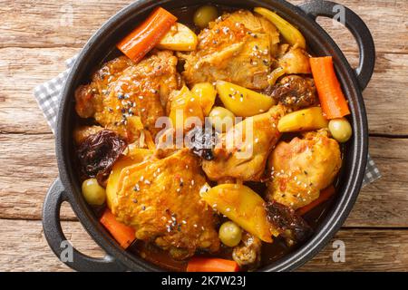 Salvadorianischen Hühnereintopf mit Chicha, Pflaumen, Karotten, Kartoffeln, Oliven und Zwiebeln aus nächster Nähe in einer Pfanne auf einem Holztisch. Horizontale Ansicht von oben Stockfoto