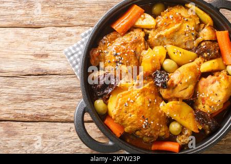 Gallo-en-Chicha-Eintopf mit Huhn, Pflaumen, Gemüse und Gewürzen, zubereitet, um einen wunderbaren Geschmack und ein Aroma aus der Nähe auf der Pfanne auf dem Holztisch zu haben. Stockfoto