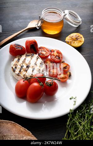 Der Camembert-Käse ist rund, gegrillt, mit goldenem Honig auf einem hölzernen Schneidebrett gegossen. Weicher selektiver Fokus, schwarzer Hintergrund.Platz zum Kopieren. Gesunde Ernährung. Vertikales Foto. Stockfoto