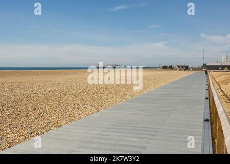 Neue Promenade am Kiesstrand von Brighton in East Sussex, England. Mit nicht erkennbaren Menschen und Pier im Hintergrund. Stockfoto