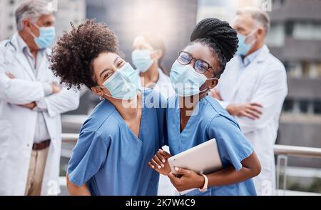 Die Zukunft des Gesundheitswesens liegt in ihren Händen. Zwei junge Ärztinnen nutzen in der Stadt ein digitales Tablet. Stockfoto
