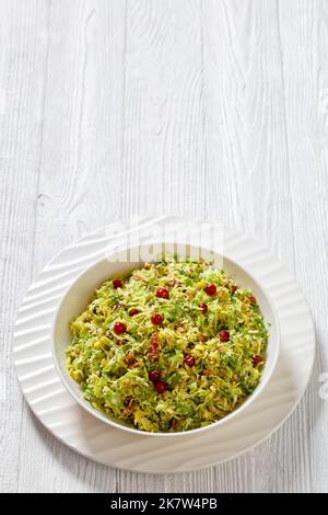 rosenkohl mit Mandeln, knusprig gebratenem Speck und Preiselbeeren in weißer Schale auf Holztisch, vertikale Ansicht von oben, freier Platz Stockfoto