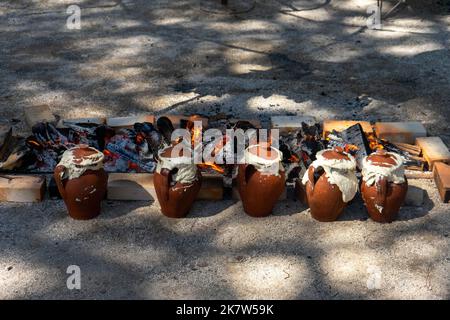 Tontöpfe mit Essen im Inneren werden auf einem langsamen Feuer in einer Feuerstelle auf einem Food Festival in Estoril, Lissabon, Portugal, gekocht. Stockfoto