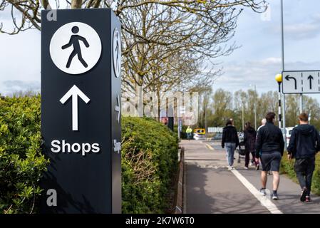 Multidirektionales Wegweiser mit Pfeil und Personenlaufsymbol, das auf Geschäfte zeigt. Stockfoto