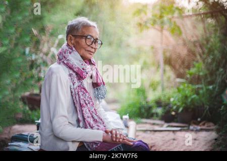 Die alte Frau saß und schaute weg, während sie über die Gesundheitsversorgung nachdachte. Stockfoto