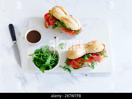 Flaches Lay mit leckeren Sandwiches mit Schinken, Mozarella und frischem Gemüse. Einfaches Mittagskonzept Stockfoto