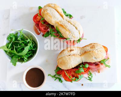 Flaches Lay mit leckeren Sandwiches mit Schinken, Mozarella und frischem Gemüse. Einfaches Mittagskonzept Stockfoto