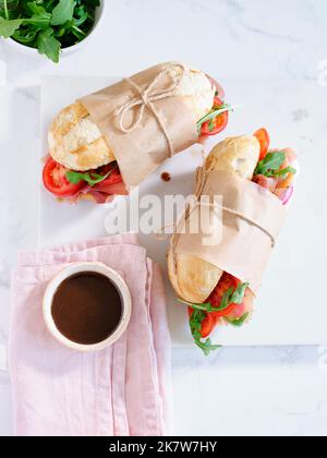 Flaches Lay mit leckeren Sandwiches mit Schinken, Mozarella und frischem Gemüse. Einfaches Mittagskonzept Stockfoto