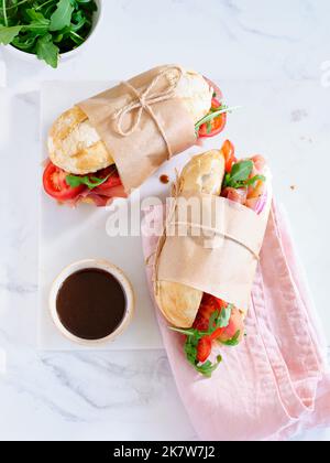 Flaches Lay mit leckeren Sandwiches mit Schinken, Mozarella und frischem Gemüse. Einfaches Mittagskonzept Stockfoto