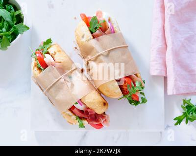 Flaches Lay mit leckeren Sandwiches mit Schinken, Mozarella und frischem Gemüse. Einfaches Mittagskonzept Stockfoto