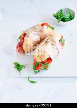 Flaches Lay mit leckeren Sandwiches mit Schinken, Mozarella und frischem Gemüse. Einfaches Mittagskonzept Stockfoto