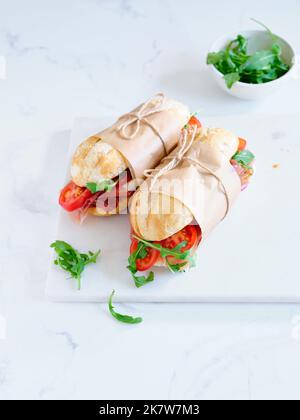 Flaches Lay mit leckeren Sandwiches mit Schinken, Mozarella und frischem Gemüse. Einfaches Mittagskonzept Stockfoto