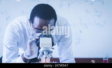 Nahaufnahme eines afrikanischen männlichen wissenschaftlichen Forschers mit Mikroskop im Labor Stockfoto