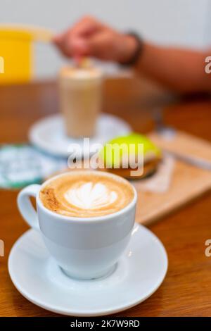 Ein Tisch in einer Bar. Es gibt zwei Kaffees und eine Torte Stockfoto