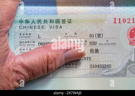 Hand mit offenem Reisepass mit chinesischem Visum in britischem Pass Stockfoto