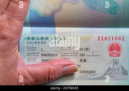Hand mit offenem Reisepass mit chinesischem Visum in britischem Pass Stockfoto