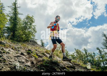 Bannoe, Russland - 31. Juli 2022: Männlicher Läufer läuft im MMK Wild Trail steil bergab Stockfoto