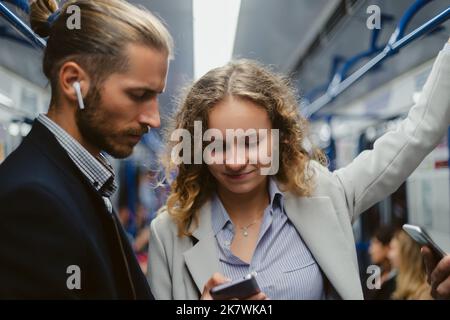 Nahaufnahme . Junge Menschen mit Smartphones fahren in einem U-Bahn-Auto. Stockfoto