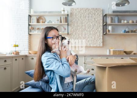 Überraschungsgeschenk, junge schöne asiatische Frau erhielt ein Geschenk von einem Haustier Jack Russell Terrier Hund, glücklich und lächelnd. Stockfoto