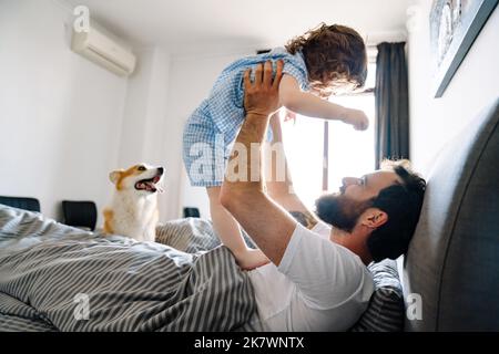 Glückliche Familie, die sich morgens im Bett entspannt und spielt Stockfoto