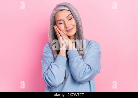 Foto von niedlichen süßen Dame Rentner gekleidet blauen Pullover Arme Wange mit Rest lächelnd isoliert rosa Farbe Hintergrund Stockfoto