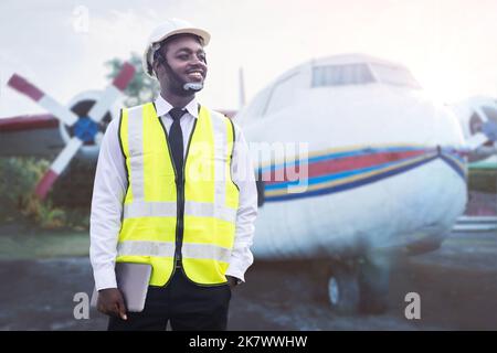 Afrikanischer Ingenieur, Techniker, der Flugzeugmotor mit Tablet in der Hand überprüft und repariert Stockfoto