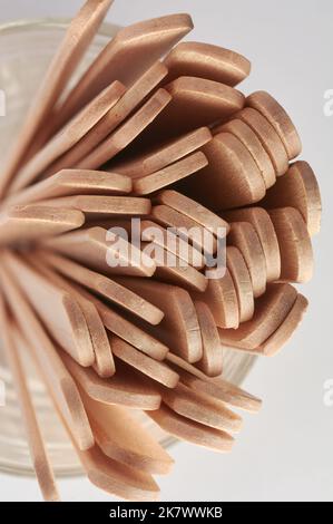 Nahaufnahme von oben mit Holzeisstäben auf einem Glas, weicher Fokus auf einem neutralen grauen Hintergrund, abstrakte Struktur Stockfoto