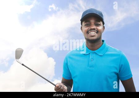 Lächelnder afrikanischer Mann mit Mütze, der im Sommer Club hält und Golf spielt Stockfoto