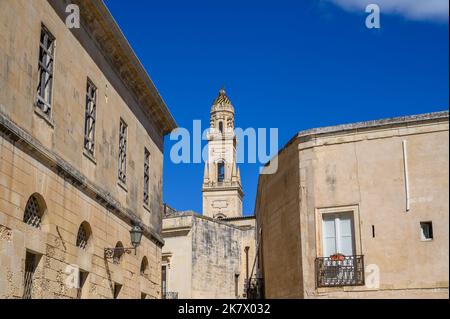 Der Glockenturm der Kathedrale von Lecce, sichtbar hinter und zwischen den Steingebäuden der Altstadt. Apulien (Apulien), Italien. Stockfoto