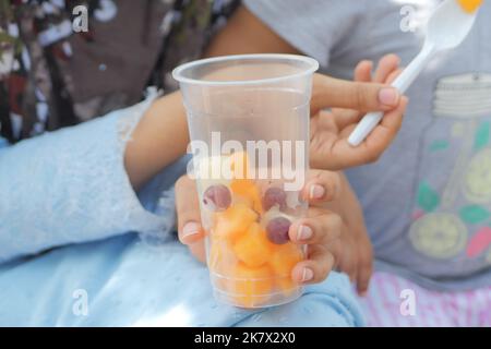 Frauen essen Papaya und Trauben aus einem Plastikbehälter Stockfoto