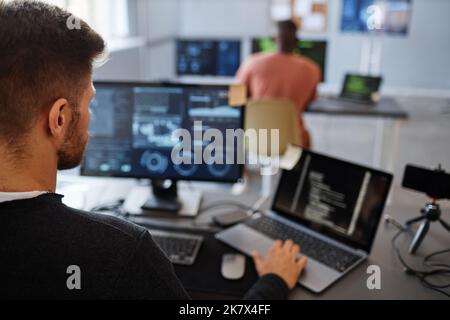 Nahaufnahme eines männlichen Software-Ingenieurs, der Computer im Büro mit Datensystemen auf dem Bildschirm verwendet, Kopierraum Stockfoto