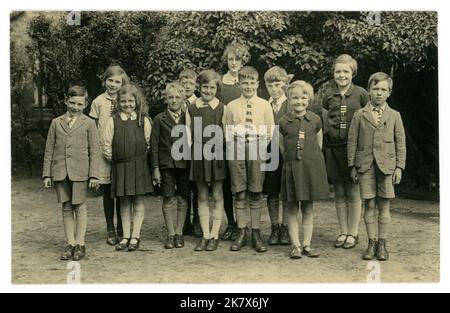 Originales Vintage-Foto, sehr klar, aus der Ära des 2. Weltkriegs, der 1930er oder 1940er Jahre einer Gruppe frecher aussehender, fröhlich riechender Schulkinder, die intelligente Schuluniform tragen, mit Kragen, Krawatten, Tuniken mit Box-Falten, Jacken und Shorts, posieren für ein Foto in ihrer Schuluniform draußen auf dem Spielplatz oder Schulhof. Einige Zeichen. 1930er 1940er Jahre gut erzogene Schulkinder. GROSSBRITANNIEN Stockfoto