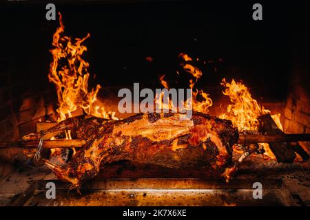 Das Lamm wird komplett auf einem Spieß auf dem Feuer gekocht. Kochen Stockfoto