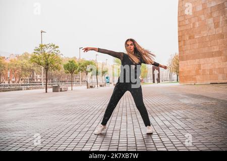 Sorglose Frau, die auf der Straße tanztCarefree Frau, die im Regen auf der Straße tanzt Stockfoto