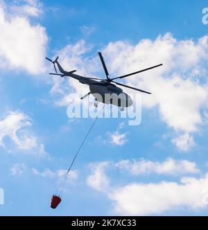 Helikopter fliegt in den Himmel und gießt Wasser auf Feuer. Gesehen auf der insel rhodos, Griechenland. Stockfoto