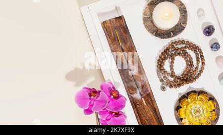 Rosenkranz, Kerzen, Duftstäbchen, Chakra-Steine und Orchideen mit Kopierraum Stockfoto