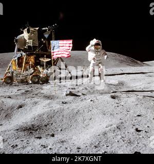 Der Astronaut John W. Young, Kommandant der Mondlandungsmission Apollo 16, springt von der Mondoberfläche, als er während der ersten außerfahrbaren Aktivität des Apollo 16 die Flagge der Vereinigten Staaten auf der Mondlandungsstelle begrüßt. Das Lunar Module „Orion“ befindet sich auf der linken Seite. Das Lunar Roving Vehicle parkt neben Orion und dem Objekt hinter Young (im Schatten des Lunar Module) Stockfoto