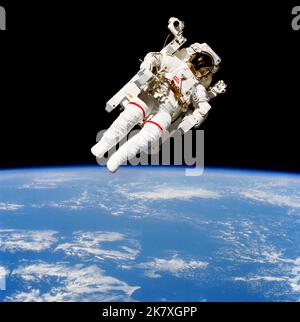 Astronaut Bruce McCandless II, STS 41-B Missionsspezialist, nimmt an einem historischen Spacewalk Teil. Er ist ein paar Meter von der Kabine des erdumkreisenden Space Shuttle Challenger entfernt abgebildet. Dieser Spacewalk stellte den ersten Einsatz eines stickstoffgetriebenen, handgesteuerten Geräts dar, das als Manned Maneuvling Unit (MMU) bezeichnet wird und eine viel größere Mobilität ermöglicht, als es früheren Spacewalks, die restriktive Haltegurte verwenden mussten, geboten wurde. Bruce McCandless II zeigt die bemannte Manövriereinheit (MMU), die im Weltraum über einer getrübten Erde schwebt. Stockfoto