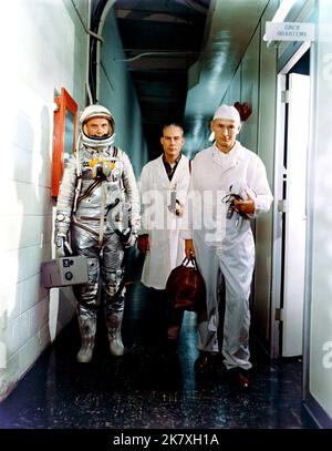 Astronaut John H. Glenn Jr. (links), Dr. William Douglas, Flugchirurg der Astronauten, und Ausrüstungsspezialist Joe Schmitt verlassen vor der Mercury-Atlas 6 (MA-6) Mission die Crew-Quartiere. Glenn ist in seinem Druckanzug und trägt die tragbare Lüftungseinheit. Stockfoto