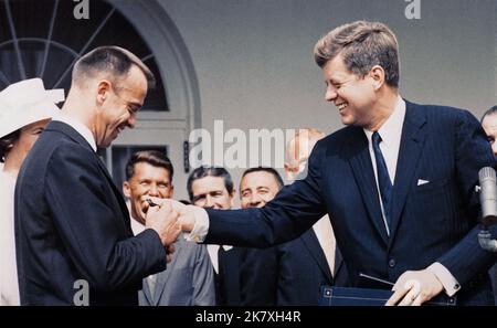 Alan Shepard – einer der ersten sieben Astronauten der NASA – wurde der erste Amerikaner im All. Präsident John F. Kennedy, rechts, verleiht am 8. Mai 1961 im Weißen Haus die Distinguished Service Medal der NASA an Astronaut Shepard bei einer Zeremonie im Rosengarten. Im Hintergrund sind die anderen Mitglieder der Mercury Seven, die ursprünglichen Astronauten der NASA. Stockfoto