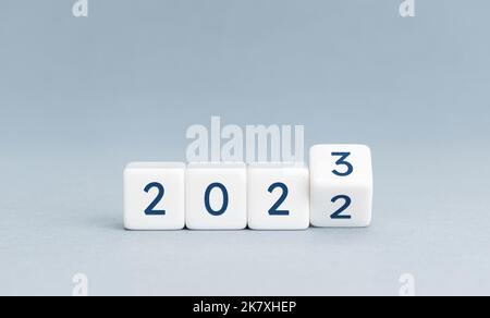 Ändern Sie die Einstellung von 2022 auf 2023 auf Würfelblöcken auf blauem Hintergrund. Das neue Jahr steht vor dem Konzept. Speicherplatz kopieren Stockfoto