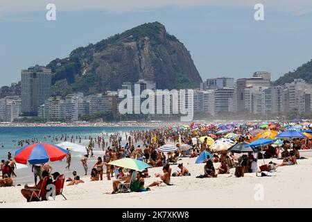 Menschenmassen am Strand von Leme und der Küste. Allgemeine Ansicht der Strandbesucher, die am sonnigen Wochenende mit bunten Sonnenschirmen in der Nähe des Ufers sonnenbaden Stockfoto