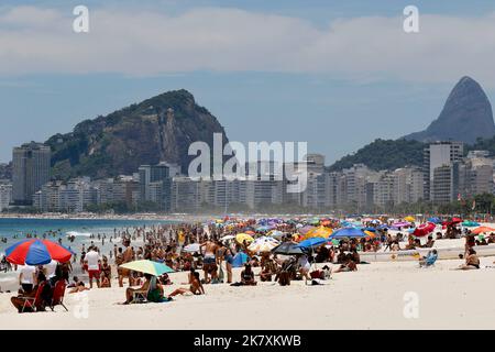 Menschenmassen am Strand von Leme und der Küste. Allgemeine Ansicht der Strandbesucher, die am sonnigen Wochenende mit bunten Sonnenschirmen in der Nähe des Ufers sonnenbaden Stockfoto