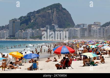 Menschenmassen am Strand von Leme und der Küste. Allgemeine Ansicht der Strandbesucher, die am sonnigen Wochenende mit bunten Sonnenschirmen in der Nähe des Ufers sonnenbaden Stockfoto