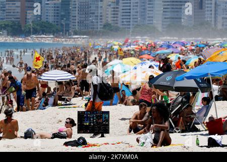 Afrikanischer Verkäufer von Einwanderern, der am Strand von der Küste entlang läuft. Schwarzer Mann, der Strandgänger nahe der Küste mit Waren verkauft, unter Menschen, die sich auf bunten Sonnenschirmen sonnen Stockfoto