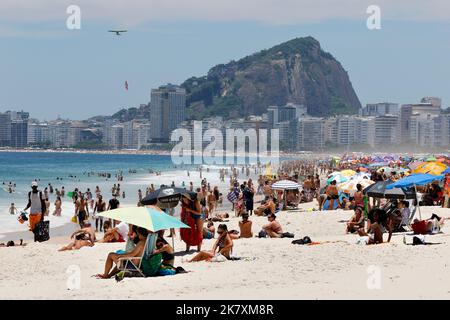 Menschenmassen am Strand von Leme und der Küste. Allgemeine Ansicht der Strandbesucher, die am sonnigen Wochenende mit bunten Sonnenschirmen in der Nähe des Ufers sonnenbaden Stockfoto