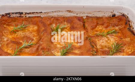 Nahaufnahme der frisch gebackenen Spinat-Lasagne mit Rosmarin-Belag, Vorderansicht Stockfoto