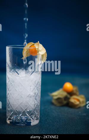 Cocktail mit Physalis alkekengi im Hintergrund gegossen und garnieren Stockfoto